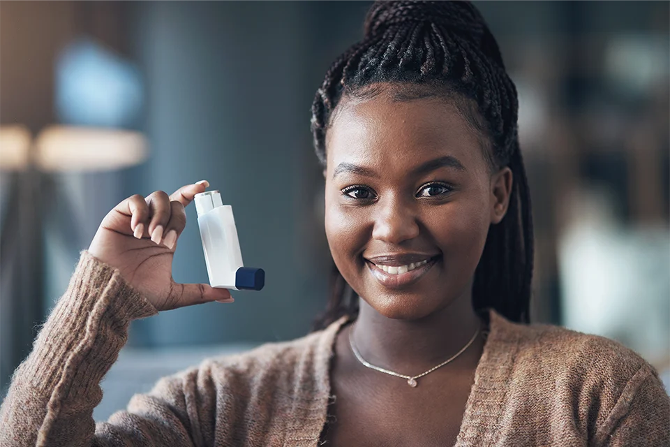 Smiling woman holding an Ipratropium inhaler in her hand.