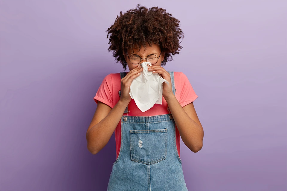 Allegra Fexofenadine provides relief for allergy sufferers like the young woman blowing her nose in the image.